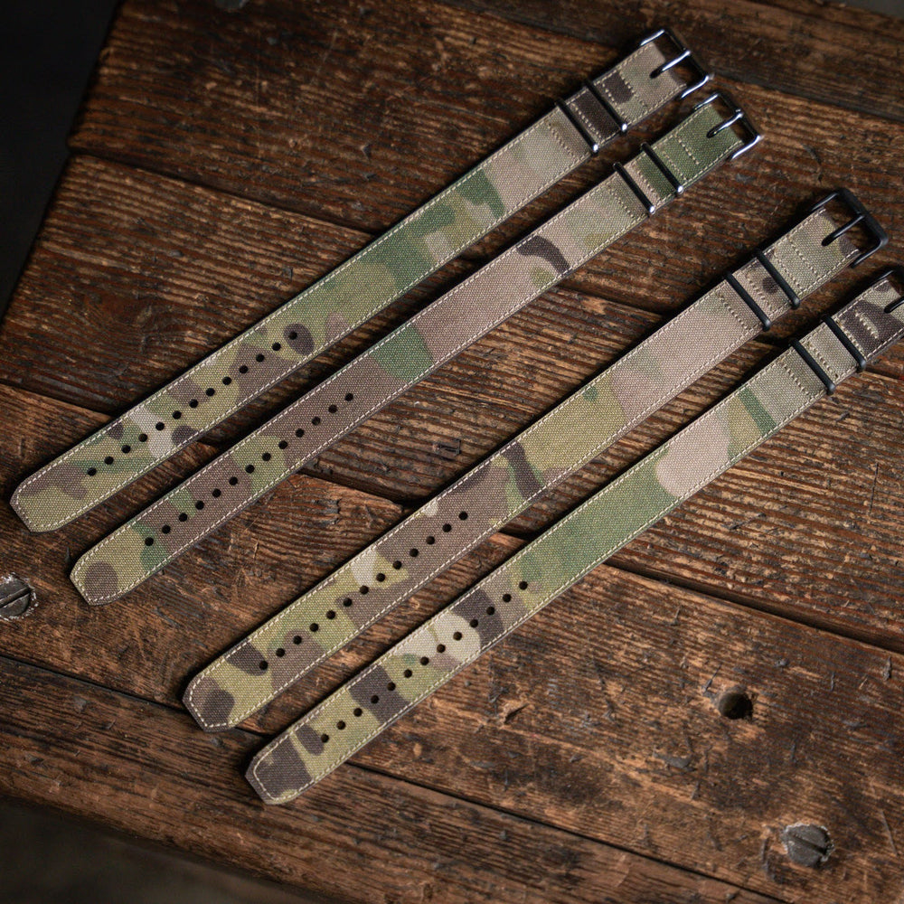 
                  
                    Three camouflage watch straps on a wooden surface
                  
                