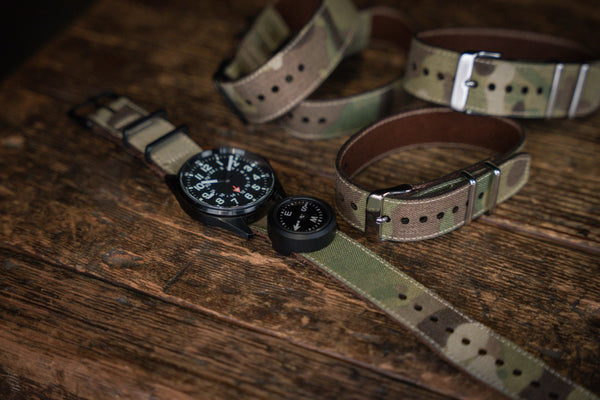 Watches with camouflage straps on a wooden surface